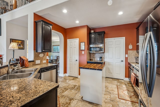 kitchen featuring wood counters, dark brown cabinetry, sink, appliances with stainless steel finishes, and decorative backsplash