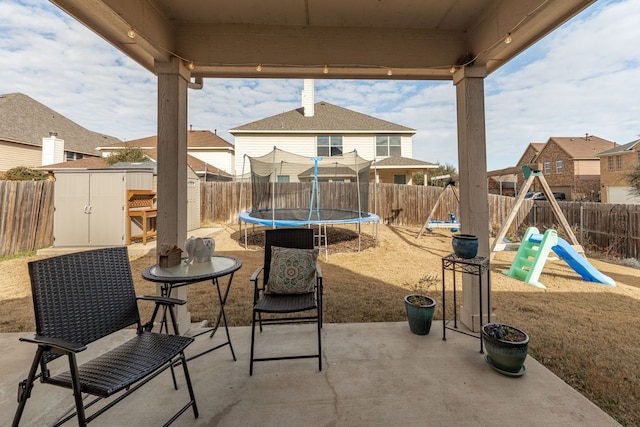 view of patio / terrace with a playground, a trampoline, and a shed