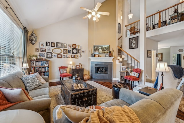 living room with wood-type flooring, high vaulted ceiling, ceiling fan, and a fireplace