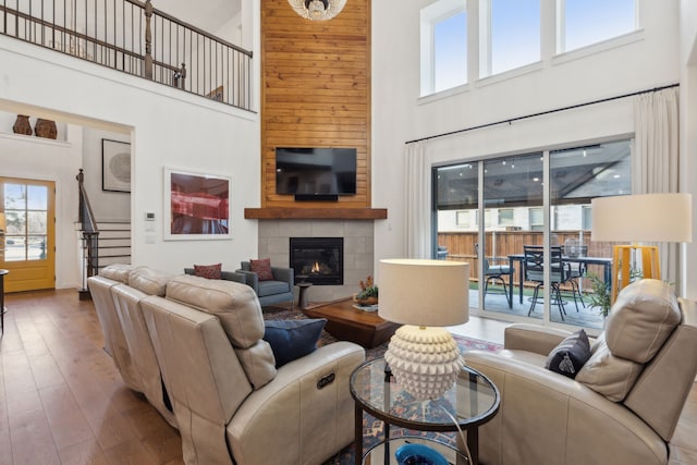 living room featuring hardwood / wood-style flooring, a fireplace, and a towering ceiling