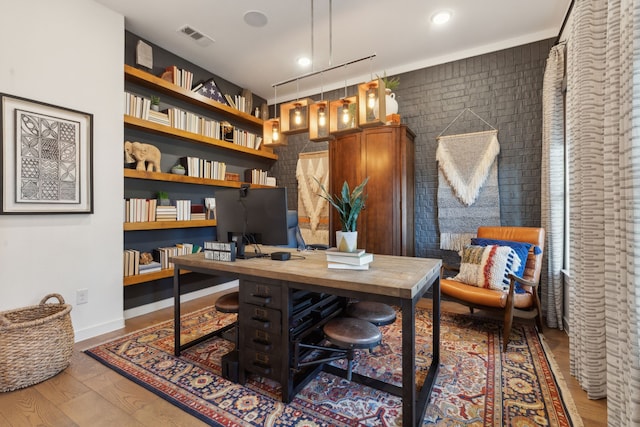 office space with hardwood / wood-style flooring and brick wall