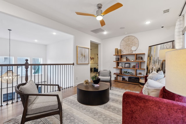 living room featuring ceiling fan with notable chandelier and light hardwood / wood-style flooring