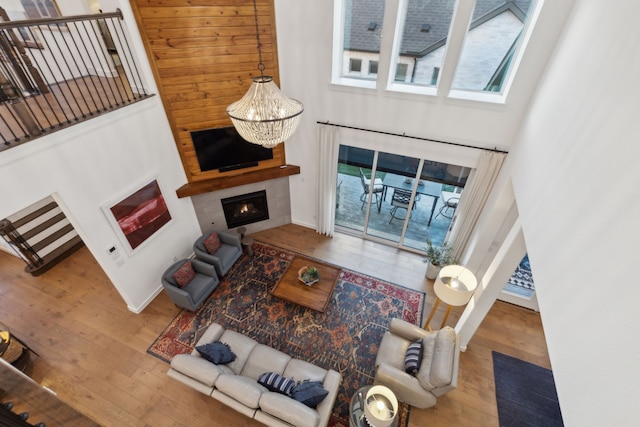 living room with hardwood / wood-style flooring, a large fireplace, a chandelier, and a towering ceiling