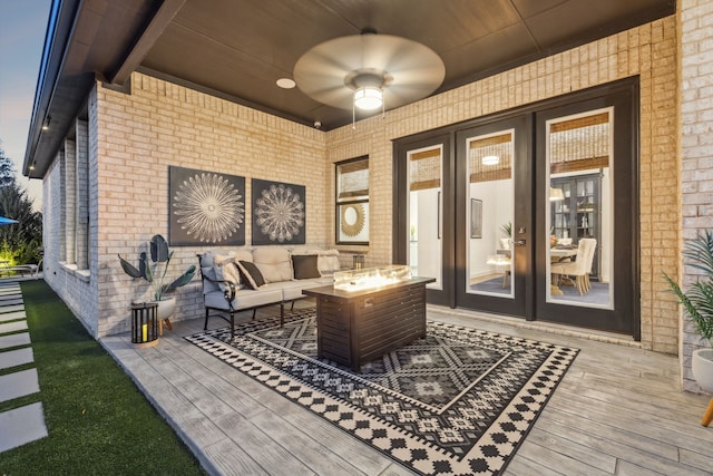 exterior space with a wooden deck, ceiling fan, and an outdoor living space with a fire pit