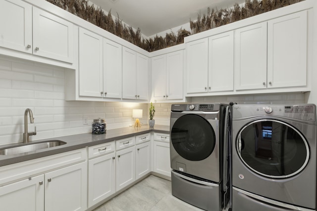 clothes washing area featuring cabinets, washing machine and clothes dryer, light tile patterned flooring, and sink