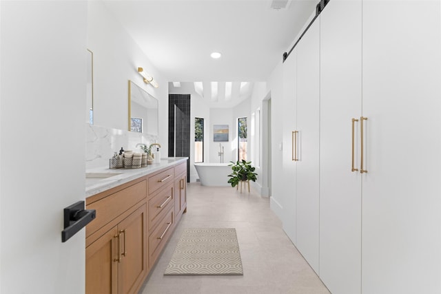 bathroom with vanity, a bathing tub, tile patterned flooring, and decorative backsplash