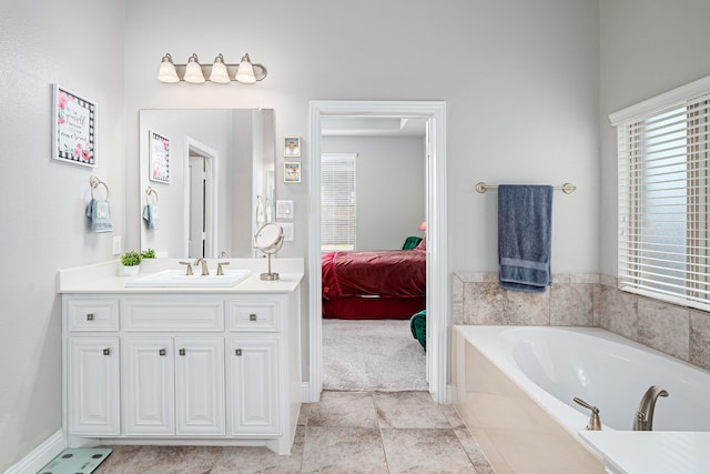 bathroom featuring tiled tub, vanity, and plenty of natural light