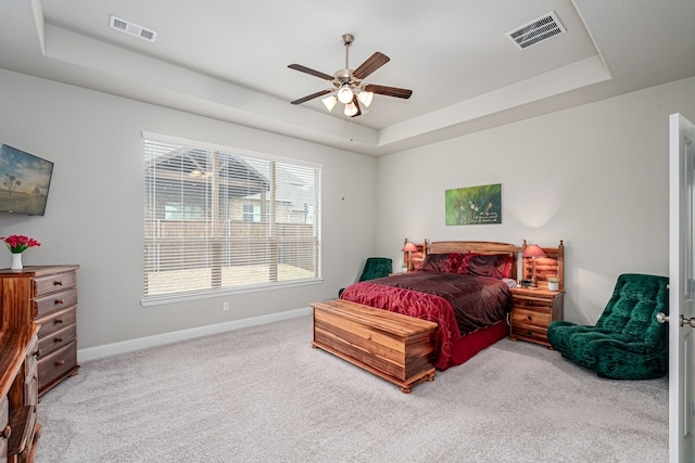 bedroom featuring a raised ceiling, ceiling fan, and carpet