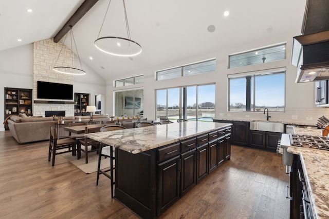 kitchen featuring stainless steel stove, a sink, beam ceiling, hardwood / wood-style floors, and tasteful backsplash