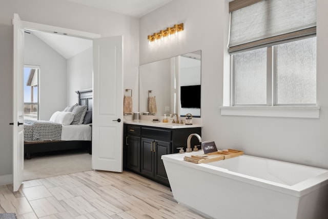 ensuite bathroom featuring lofted ceiling, a soaking tub, ensuite bath, and vanity