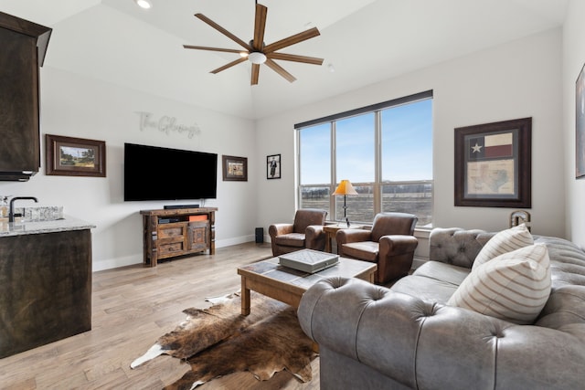 living room featuring ceiling fan, baseboards, lofted ceiling, and light wood-style floors