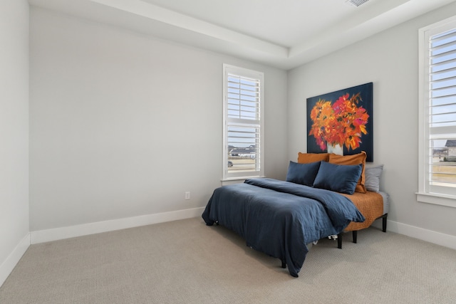 bedroom featuring light carpet, multiple windows, and baseboards