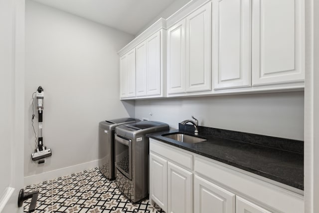 laundry area with cabinet space, baseboards, separate washer and dryer, and a sink