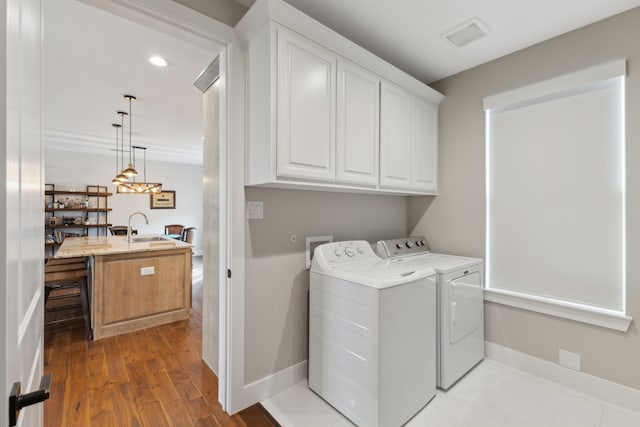 laundry room with cabinet space, baseboards, visible vents, separate washer and dryer, and a sink