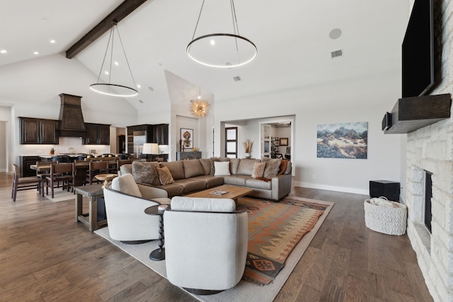 living room with dark hardwood / wood-style flooring, a stone fireplace, high vaulted ceiling, and beamed ceiling