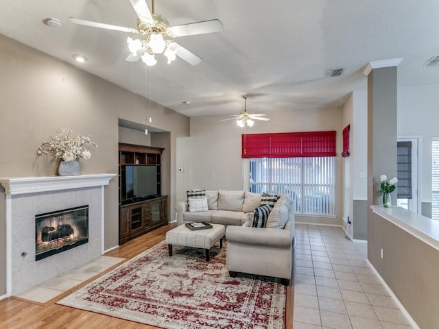 living room featuring light tile patterned flooring, ceiling fan, and a tiled fireplace