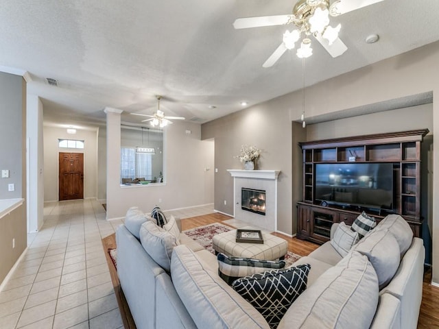 living room featuring light tile patterned floors, a fireplace, and ceiling fan