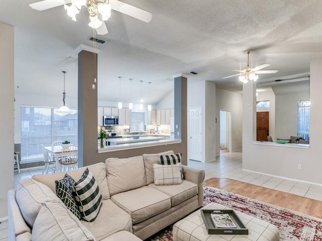 living room with lofted ceiling, a healthy amount of sunlight, light hardwood / wood-style floors, and a textured ceiling