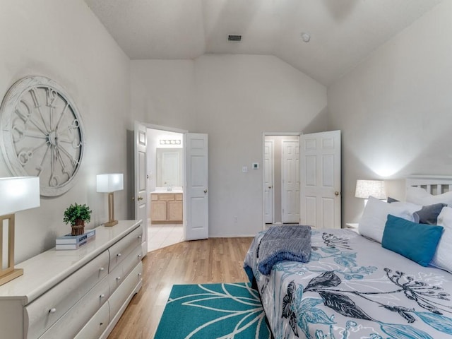 bedroom featuring high vaulted ceiling, connected bathroom, and light wood-type flooring