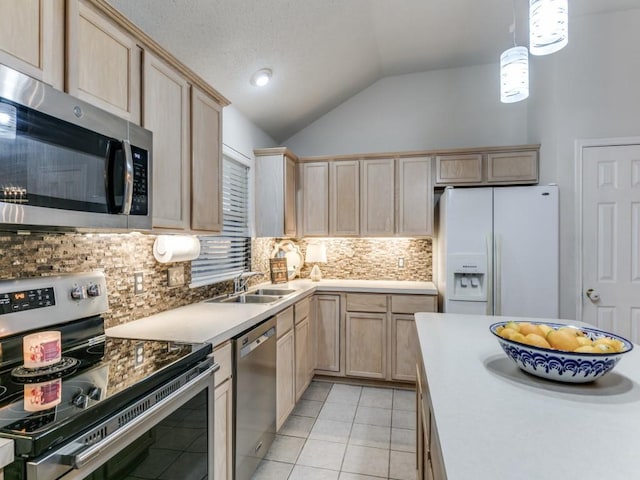 kitchen with stainless steel appliances, vaulted ceiling, sink, and light brown cabinetry