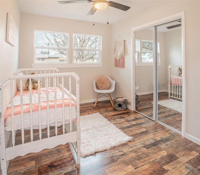 bedroom with hardwood / wood-style floors, a closet, a nursery area, and ceiling fan