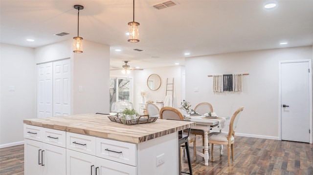 kitchen with wood counters, white cabinets, hanging light fixtures, a center island, and dark wood-type flooring