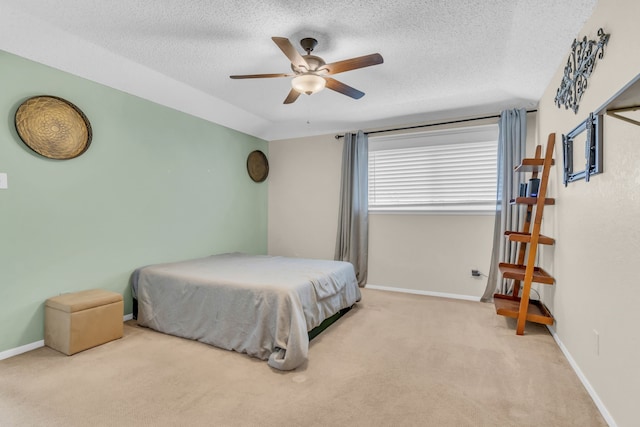 bedroom with ceiling fan, light colored carpet, and a textured ceiling