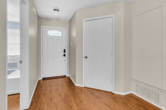 foyer entrance featuring plenty of natural light, light hardwood / wood-style floors, and a textured ceiling