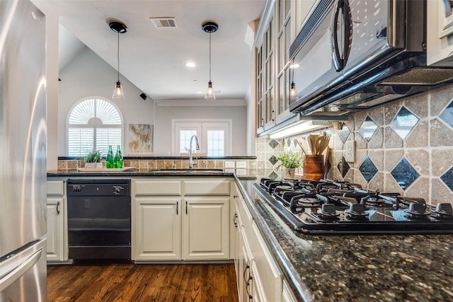 kitchen featuring sink, dark stone countertops, hanging light fixtures, stainless steel appliances, and dark hardwood / wood-style floors