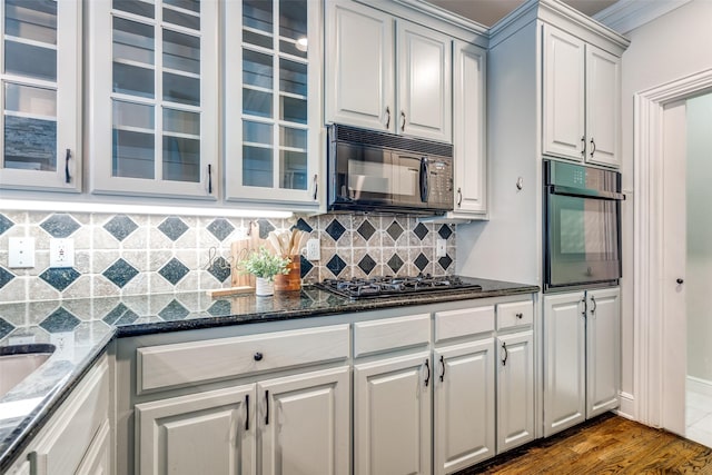 kitchen featuring dark stone countertops, white cabinets, dark hardwood / wood-style flooring, backsplash, and black appliances