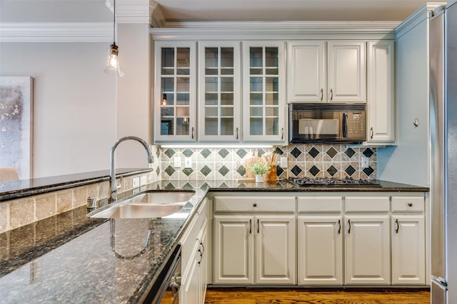 kitchen with pendant lighting, sink, dark stone countertops, ornamental molding, and black appliances