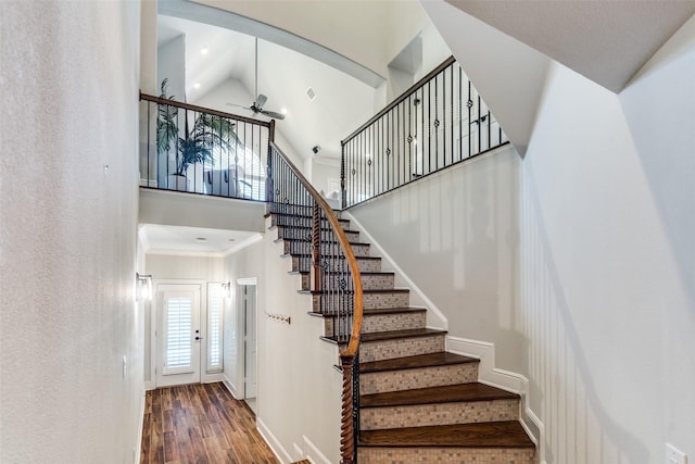 stairs with crown molding, hardwood / wood-style flooring, high vaulted ceiling, and ceiling fan