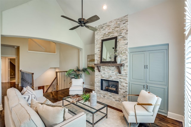 living room with ceiling fan, a stone fireplace, hardwood / wood-style floors, and high vaulted ceiling