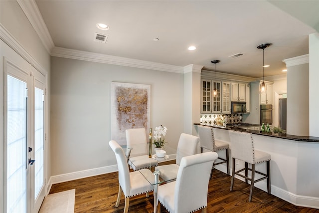 dining area with dark hardwood / wood-style flooring and crown molding