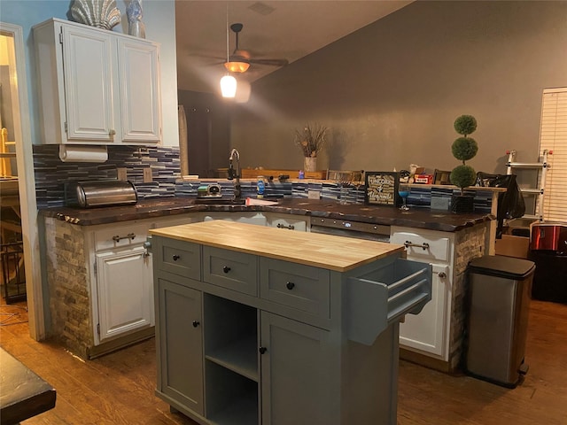 kitchen with wood counters, dark wood-type flooring, a center island, and white cabinets