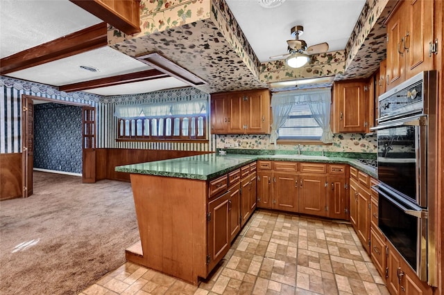 kitchen featuring sink, dark stone countertops, ceiling fan, beamed ceiling, and black double oven