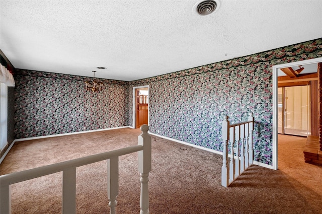 spare room featuring a textured ceiling and carpet flooring