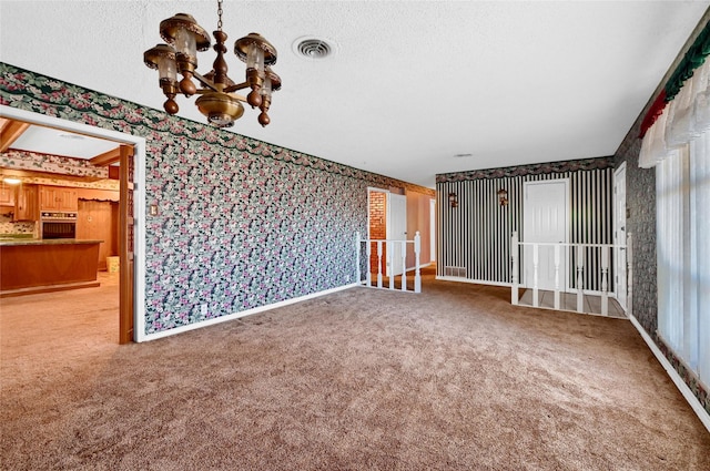 unfurnished living room with carpet, a notable chandelier, and a textured ceiling