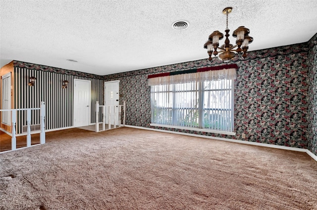 unfurnished room featuring carpet floors, a textured ceiling, and a notable chandelier