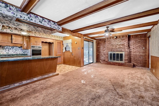 interior space with a fireplace, beam ceiling, wooden walls, and light colored carpet