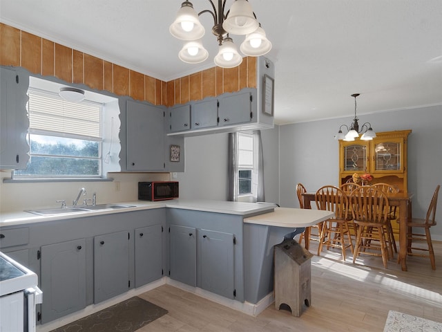 kitchen featuring sink, gray cabinetry, a chandelier, hanging light fixtures, and kitchen peninsula