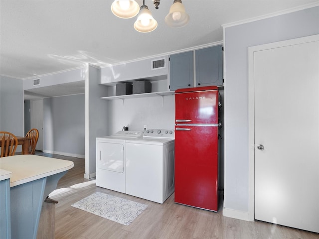 washroom with crown molding, washing machine and clothes dryer, and light hardwood / wood-style flooring