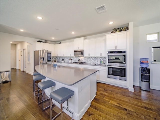 kitchen with sink, stainless steel appliances, a kitchen breakfast bar, white cabinets, and a center island with sink