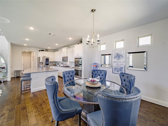 dining space with sink, a notable chandelier, and dark wood-type flooring