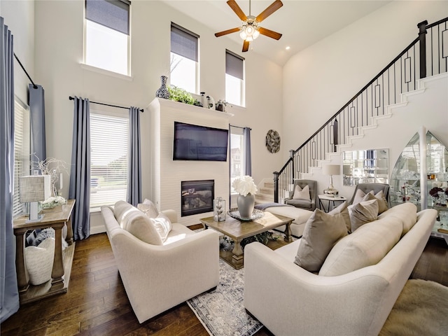 living room with ceiling fan, a towering ceiling, and dark hardwood / wood-style floors