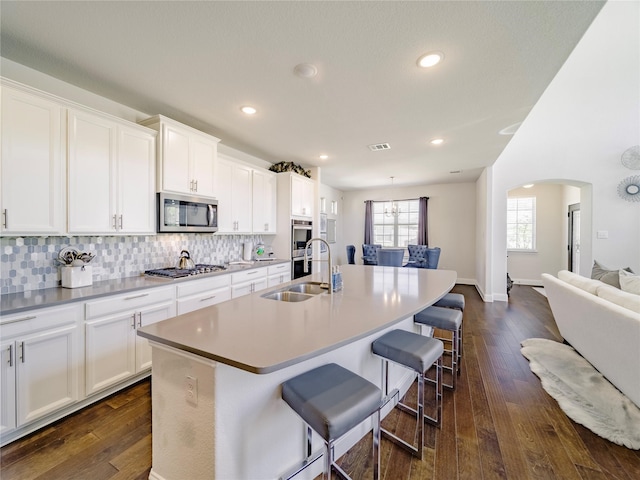 kitchen featuring sink, a kitchen breakfast bar, stainless steel appliances, an island with sink, and white cabinets