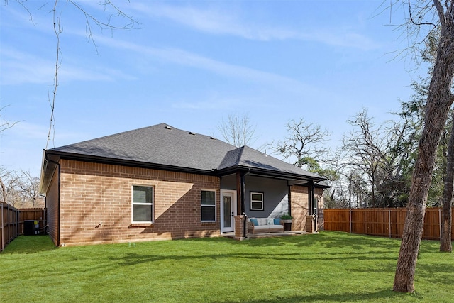 rear view of property with central AC unit and a lawn