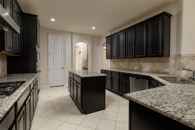 kitchen featuring appliances with stainless steel finishes, light stone counters, and dark cabinetry