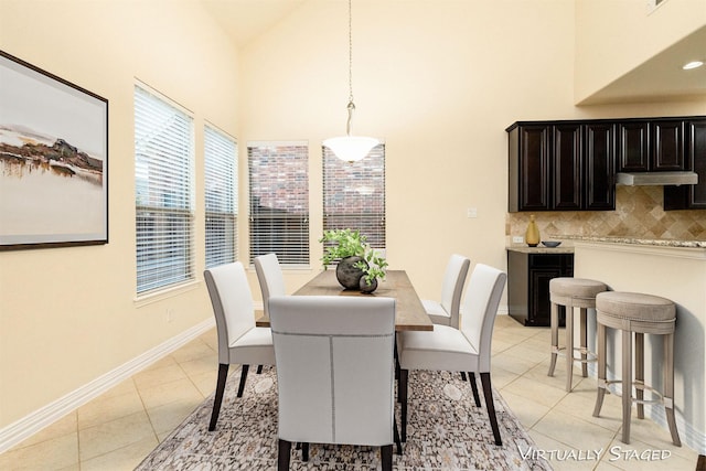 dining room with high vaulted ceiling, baseboards, and light tile patterned floors