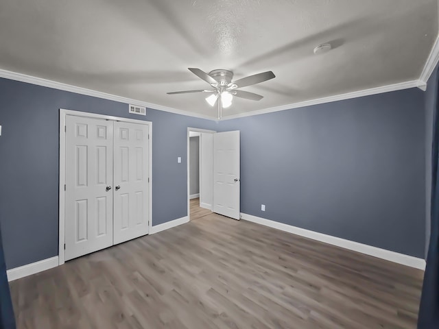 unfurnished bedroom with hardwood / wood-style flooring, ceiling fan, ornamental molding, and a closet